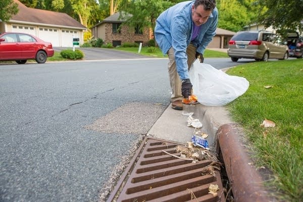 Paul Erdmann removes debris from a storm drain in Bloomington.