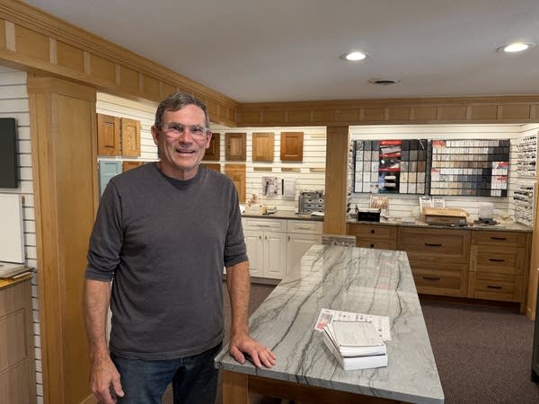 A man poses for a photo next to a granite kitchen island.