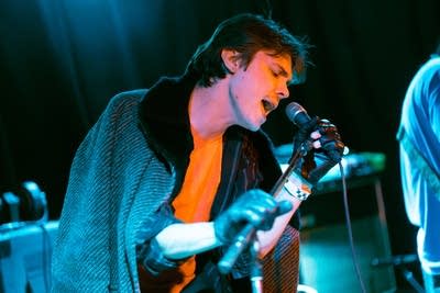 A musician sings into a microphone onstage