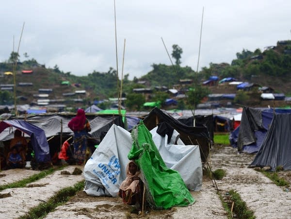 A Rohingya woman sits next to a newly built shelter