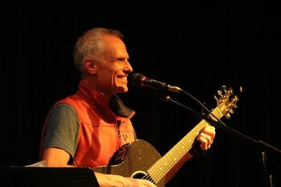 A man smiles while playing guitar onstage