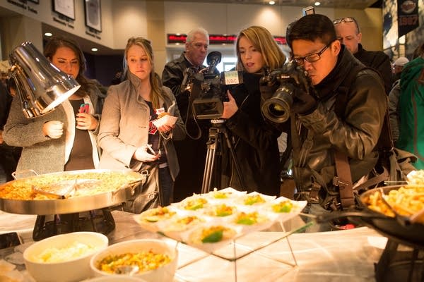 Members of the media crowd around new foods.