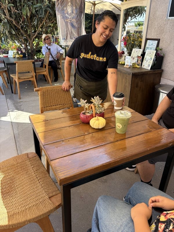 A woman brings a coffee to a table.