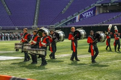 A marching band performs on the field of a football stadium.