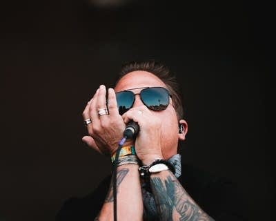 A musician plays harmonica on a large outdoor stage