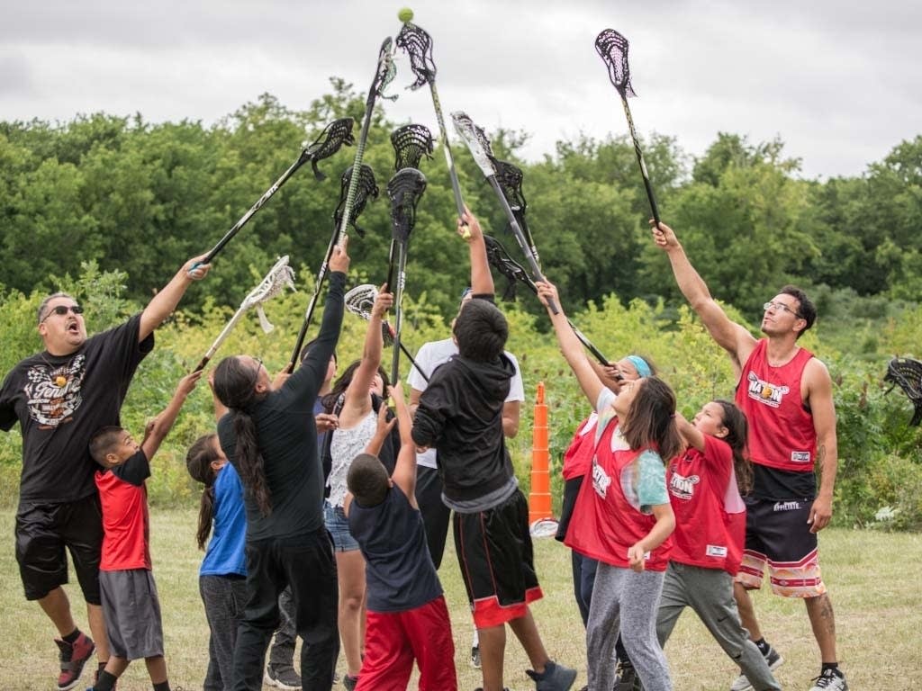Lacrosse players raise their sticks.