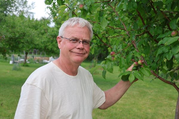 A man poses next to a tree