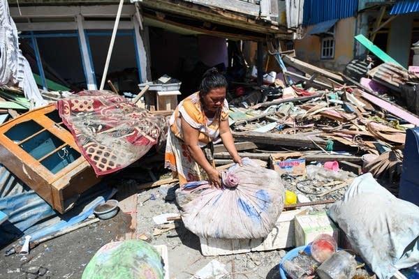 A quake survivor salvages items from the debris of a house.