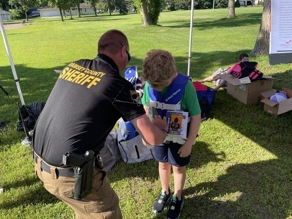 A police officer helps a young child with a life vest.