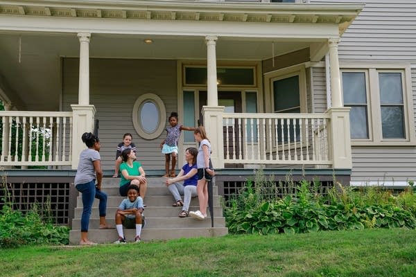 A building has people sitting outside on the front porch.