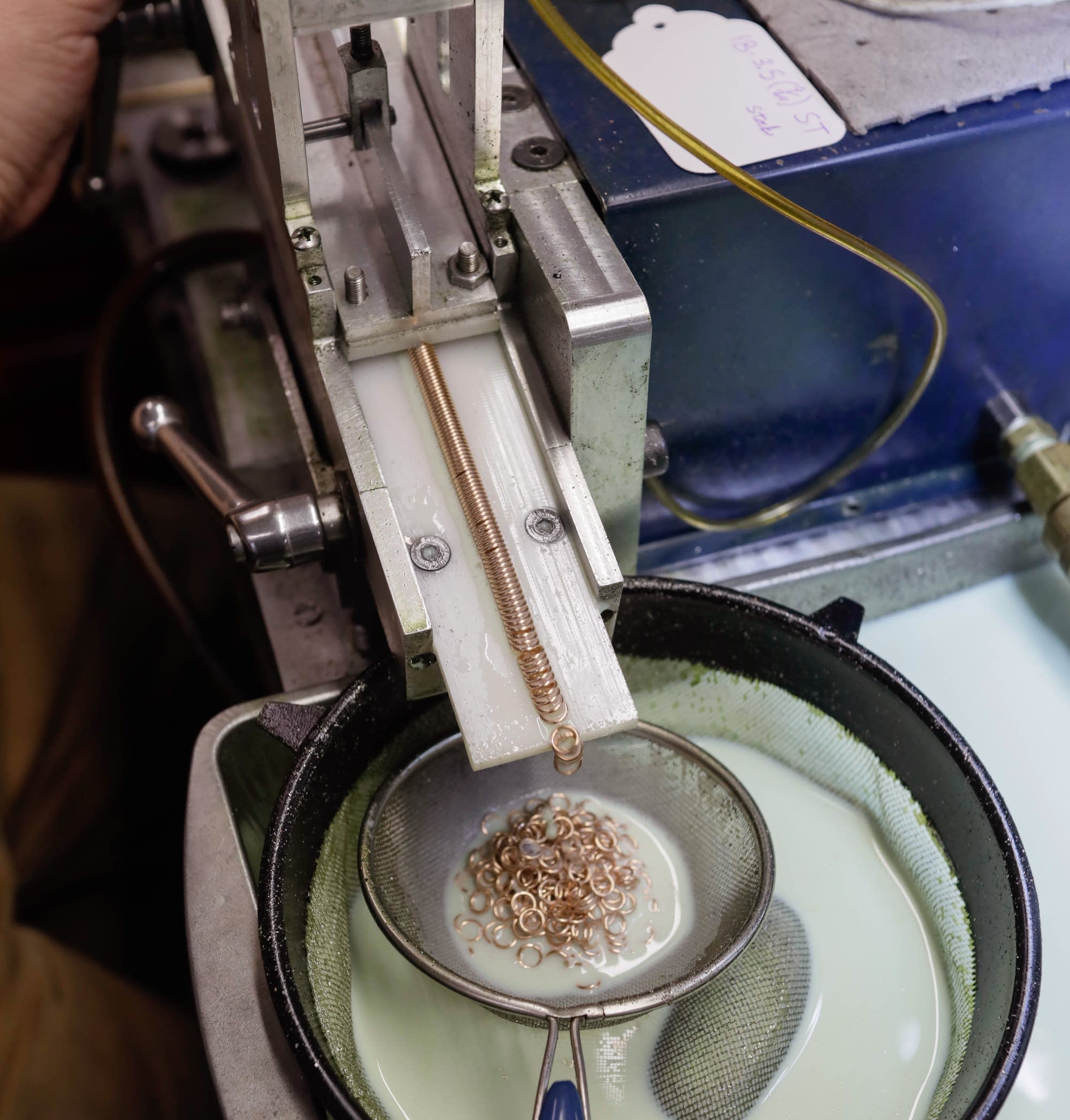 A coiled piece of wire passes through a cutter to form individual links.