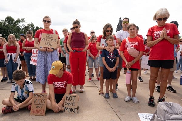 People with cardboard signs gather at a gun violence rally.
