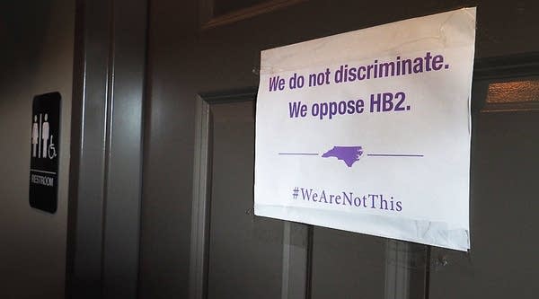 A unisex sign and the 'We Are Not This' slogan are outside a bathroom at Bull McCabes Irish Pub on May 10, 2016, in Durham, North Carolina. 