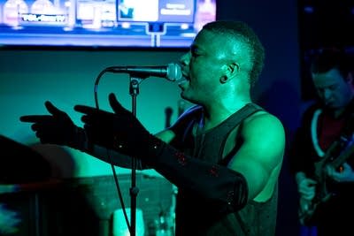 A man gestures and sings onstage in a music venue