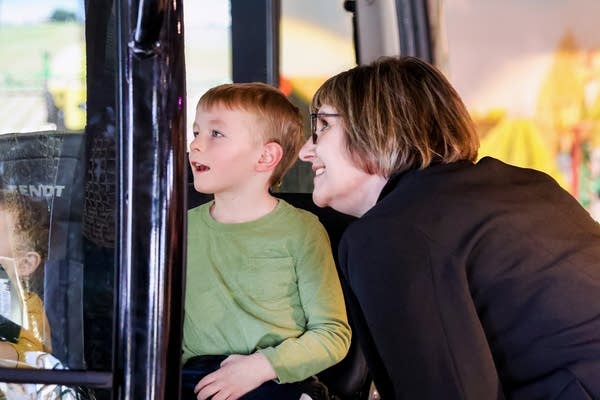 A child looks out at an interactive exhibit. A woman kneels down to look with him.