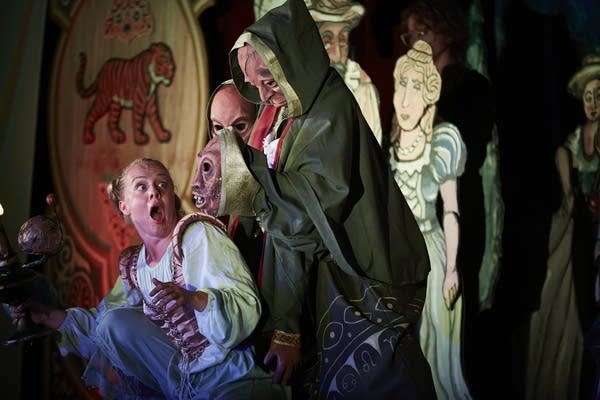 An actor shows surprise as a puppet approaches from upstage