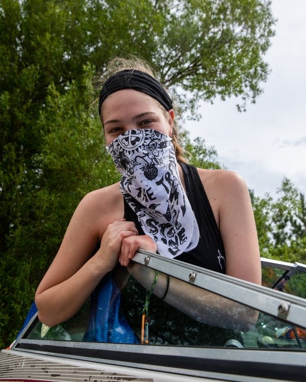 An activist with a face bandana sits in a boat.