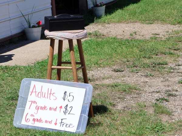 a handwritten sign leans against a wooden stool