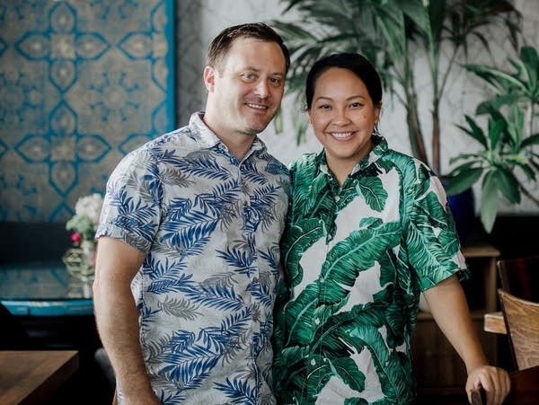 Two people stand in a photo inside a restaurant.