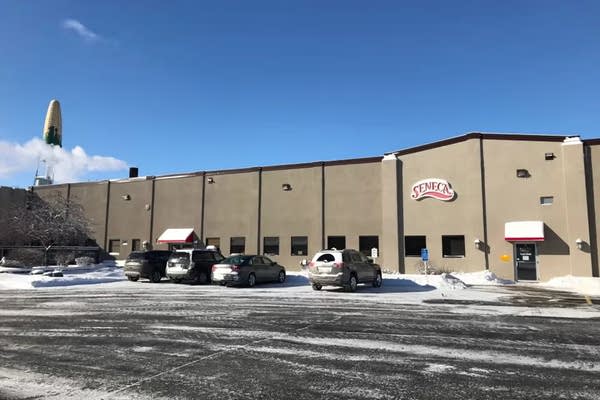 Several cars are parked outside a building with the sign "Seneca" on a snowy day.