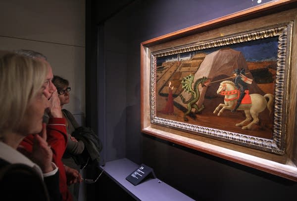 People look at a painting of St George slaying the dragon