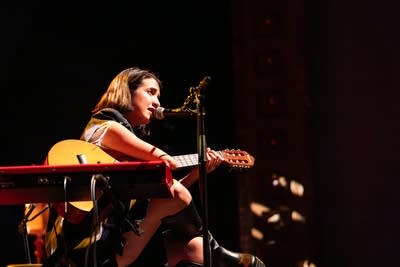 A musician sings and plays guitar onstage