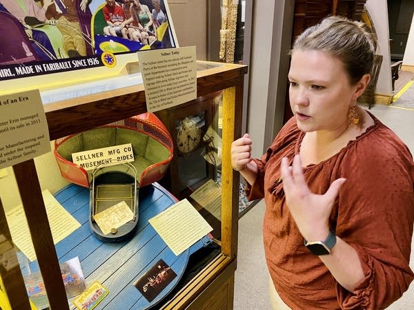 A woman stands next to a historical display.