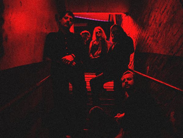 Five guys stand together in a dimly lit stairway