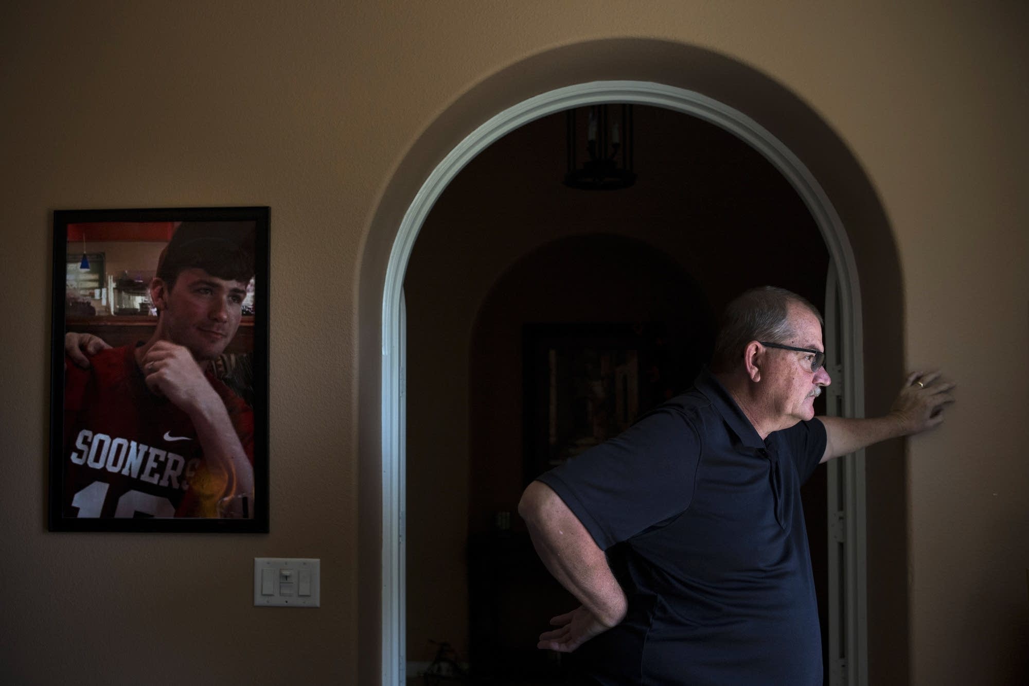 Doug Biggers pauses in his home office next to a photo of his son.