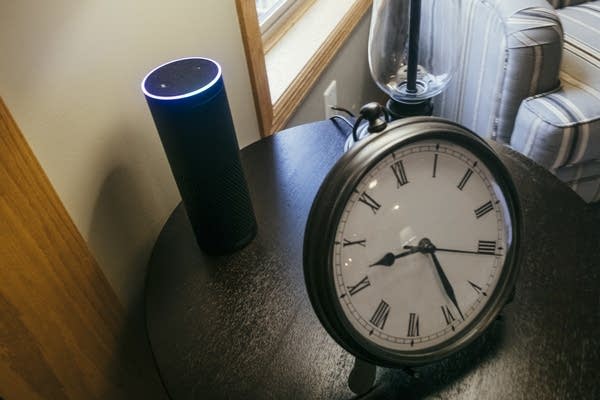 An Amazon Echo sits on an end table. 