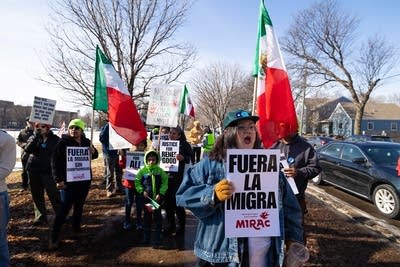 People carry Mexican flags and hold signs reading "Fuera la migra."