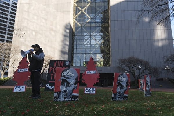 a man speaks into a megaphone outside a government building