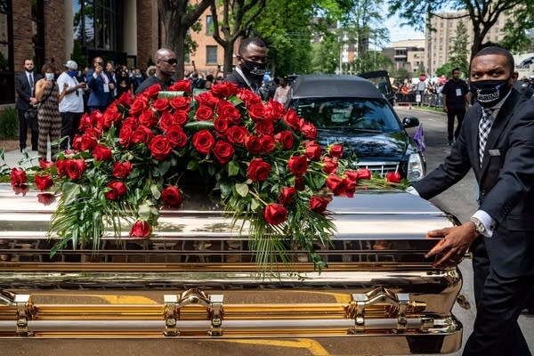 A casket with roses on top of it.