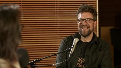 Two men have a conversation in a recording studio