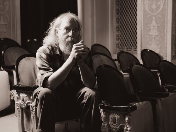 A man sits thoughtfully on a seat in a theater