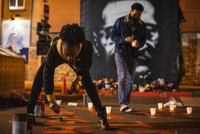 A person leans down to paint