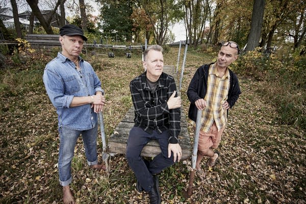Todd Menton, Drew Miller, and Mo Engel lean on a dock amid fall leaves.