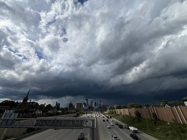 Dark gray clouds hang over Minneapolis, seen from an interstate overpass.