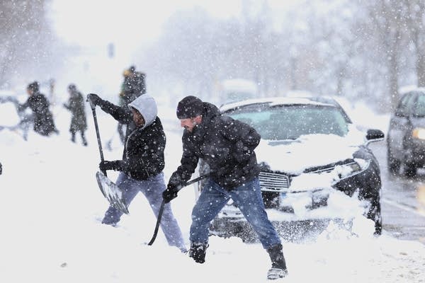 John Bauer, right, and Fahmi Osman help residents dig their vehicles out.