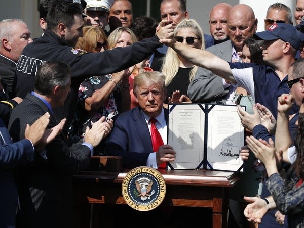 President Trump holds up the signed H.R. 1327 bill.