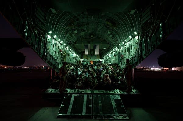 In this handout provided by the U.S. Air Force, an air crew assigned to the 816th Expeditionary Airlift Squadron assists evacuees aboard a C-17 Globemaster III aircraft in support of the Afghanistan evacuation at Hamid Karzai International Airport on August 21, 2021 in Kabul, Afghanistan. 