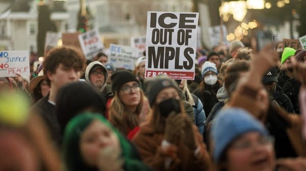 A person holds a sign that reads "ICE OUT OF MPLS" at a protest.
