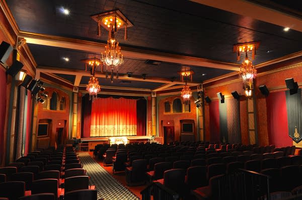A view inside a newly renovated movie theater with warm lighting and red walls and curtains.