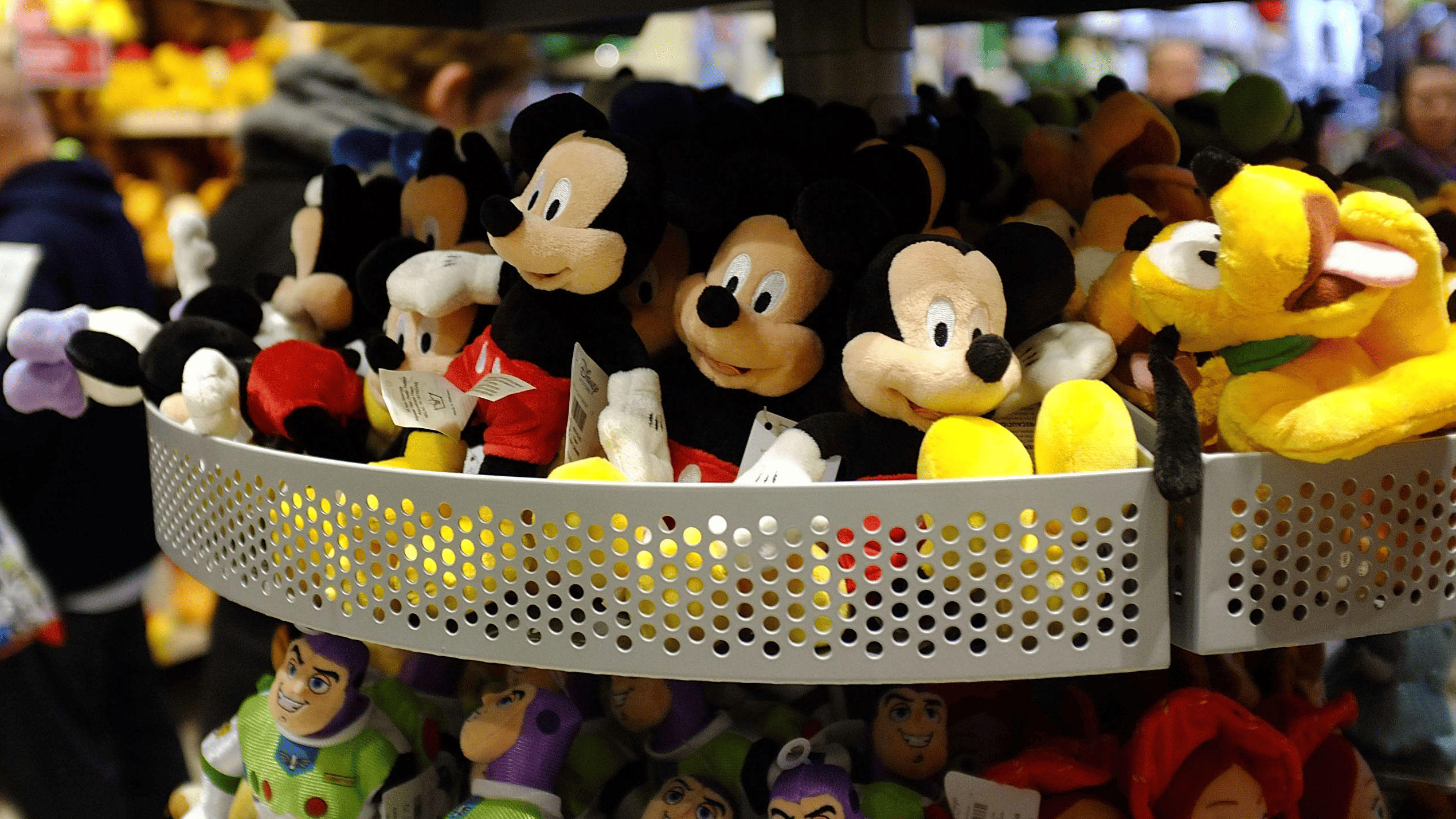 Stuffed Mickey Mouse, Buzz Lightyear and Pluto plush toys are displayed on a rack at a Disney store in New York.
