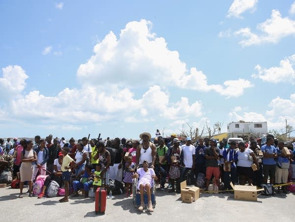 People wait to be evacuated in private boats