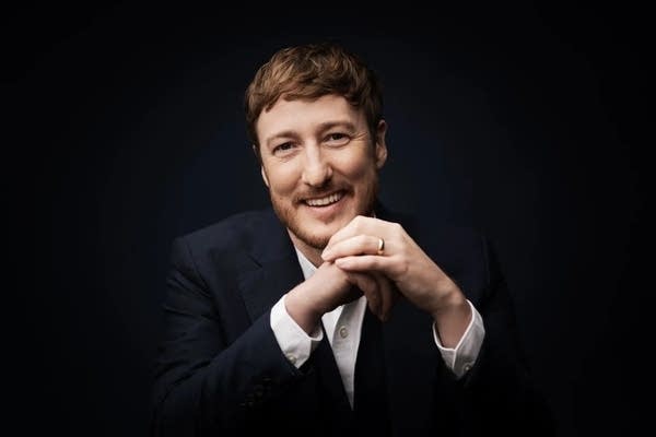 A man in a suit smiles and poses for a portrait