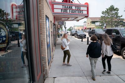 A group of women walk under a theater marquis that reads, "Thank you firefighters."