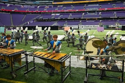 A marching band performs on the field of a football stadium.