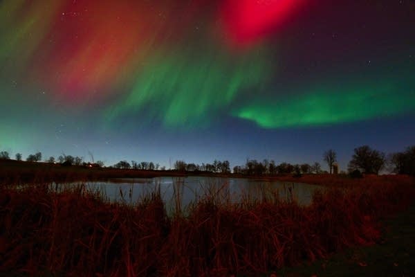 A view of the night sky with green and red auroras.