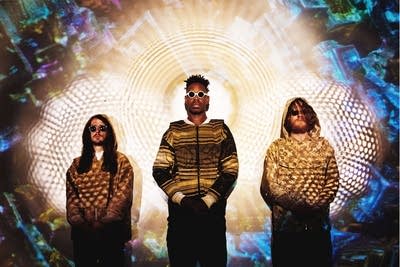 Three men standing in a bright projection